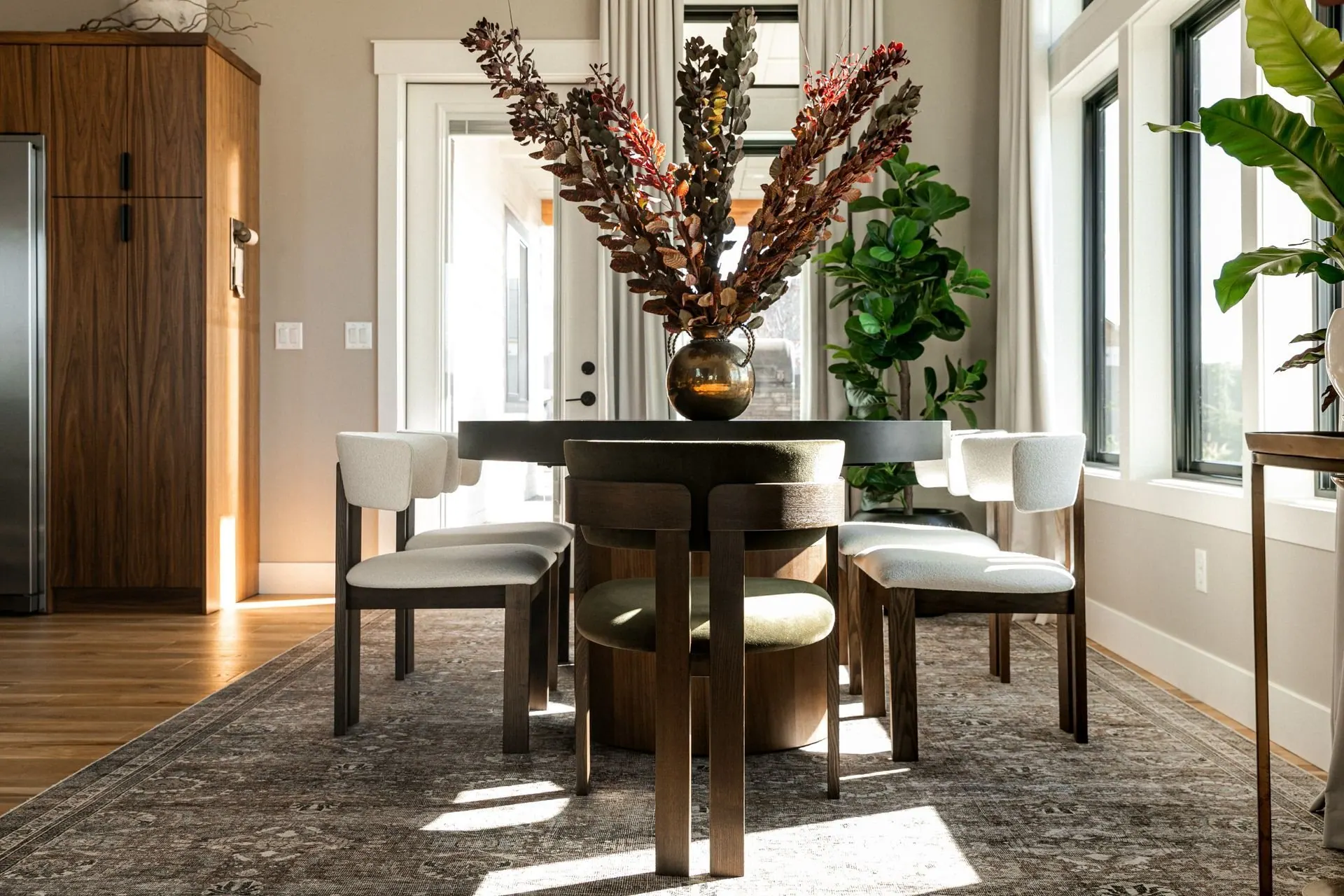 Warm dining area with a round wood table and large windows framing the valley