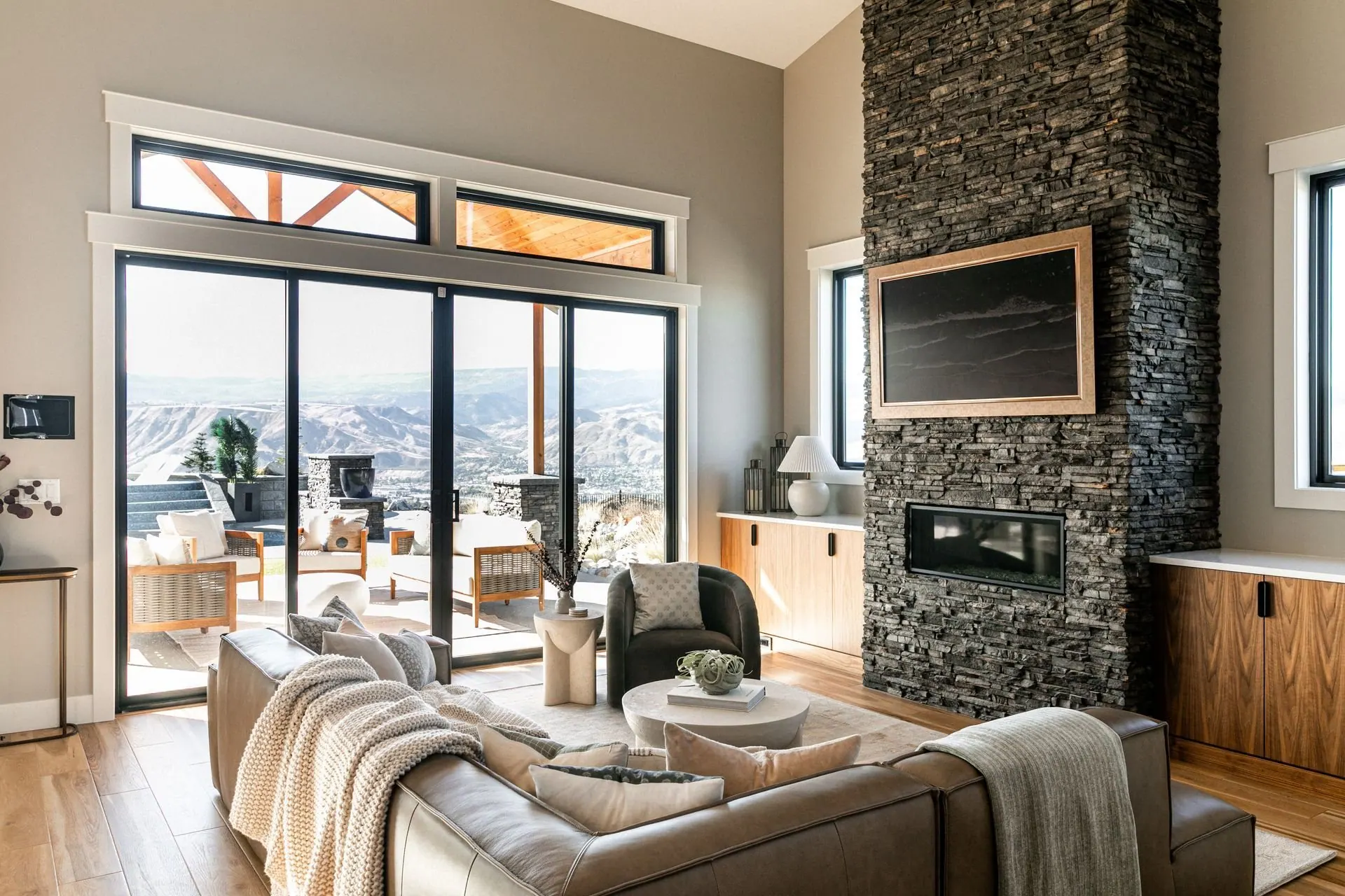 New construction living room with a stone fireplace and floor-to-ceiling glass overlooking the valley