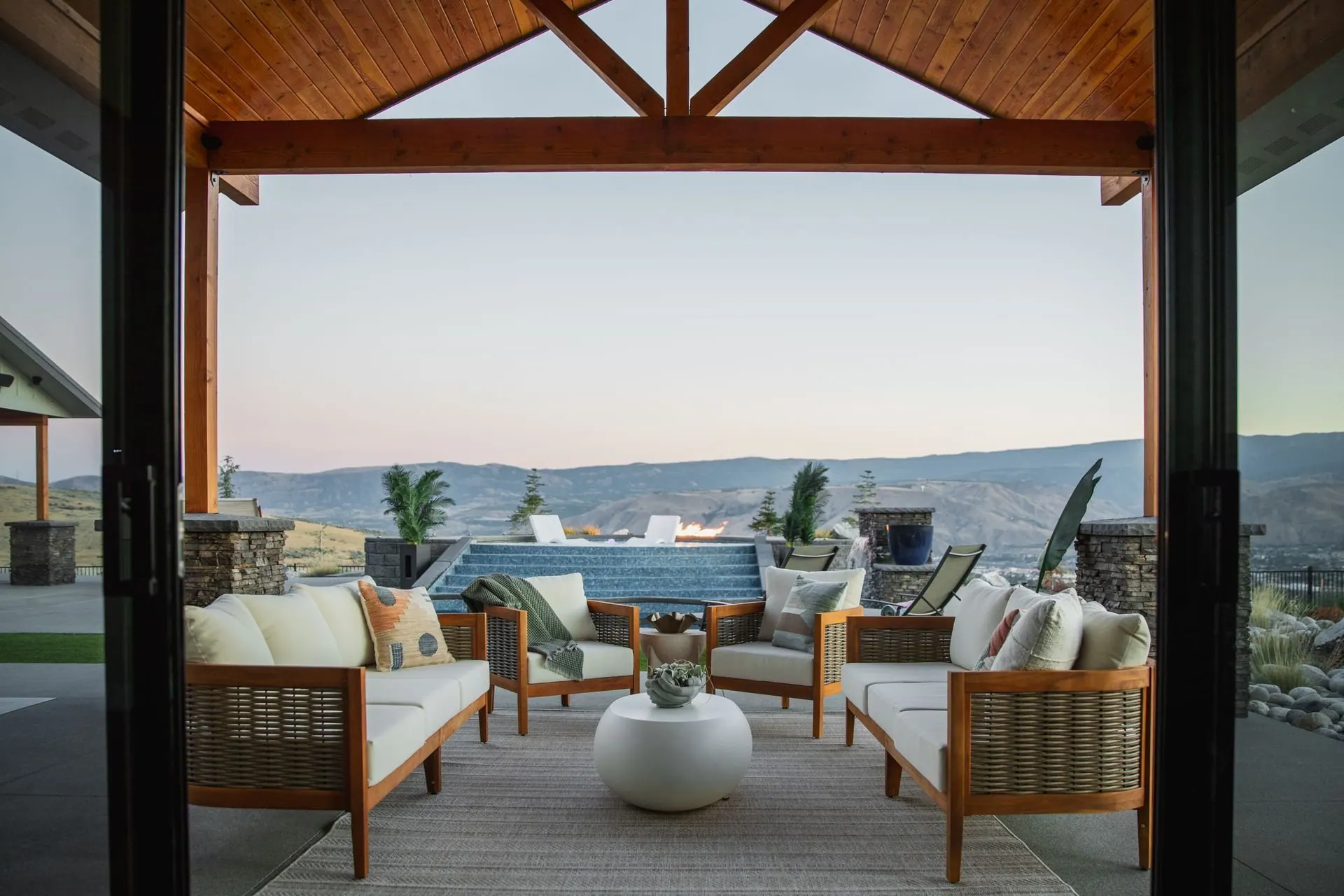 Covered outdoor patio with timber beams, comfortable seating and mountain views