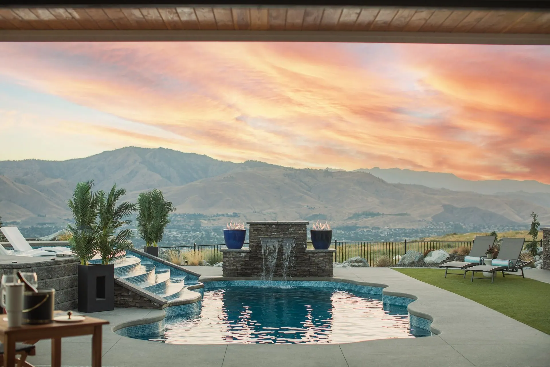 Backyard pool at sunset with loungers along the deck and the mountains beyond, at a Pacific Northwest lake home
