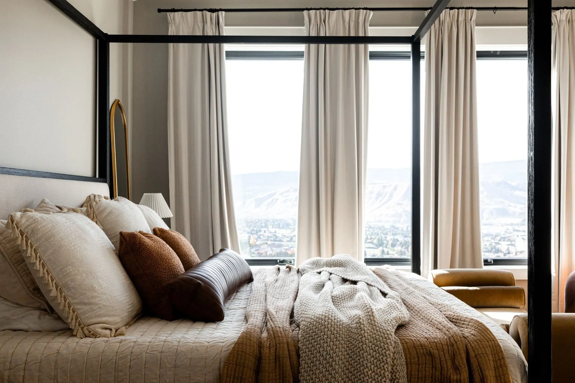 Serene primary bedroom with a canopy bed and layered neutral bedding