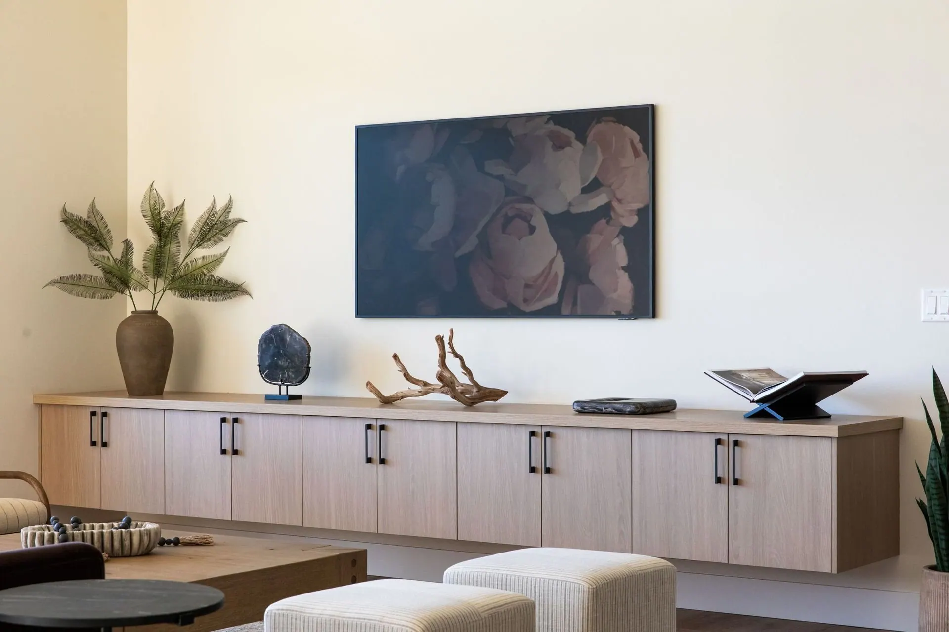 Long light wood credenza styled beneath large artwork in an open living space