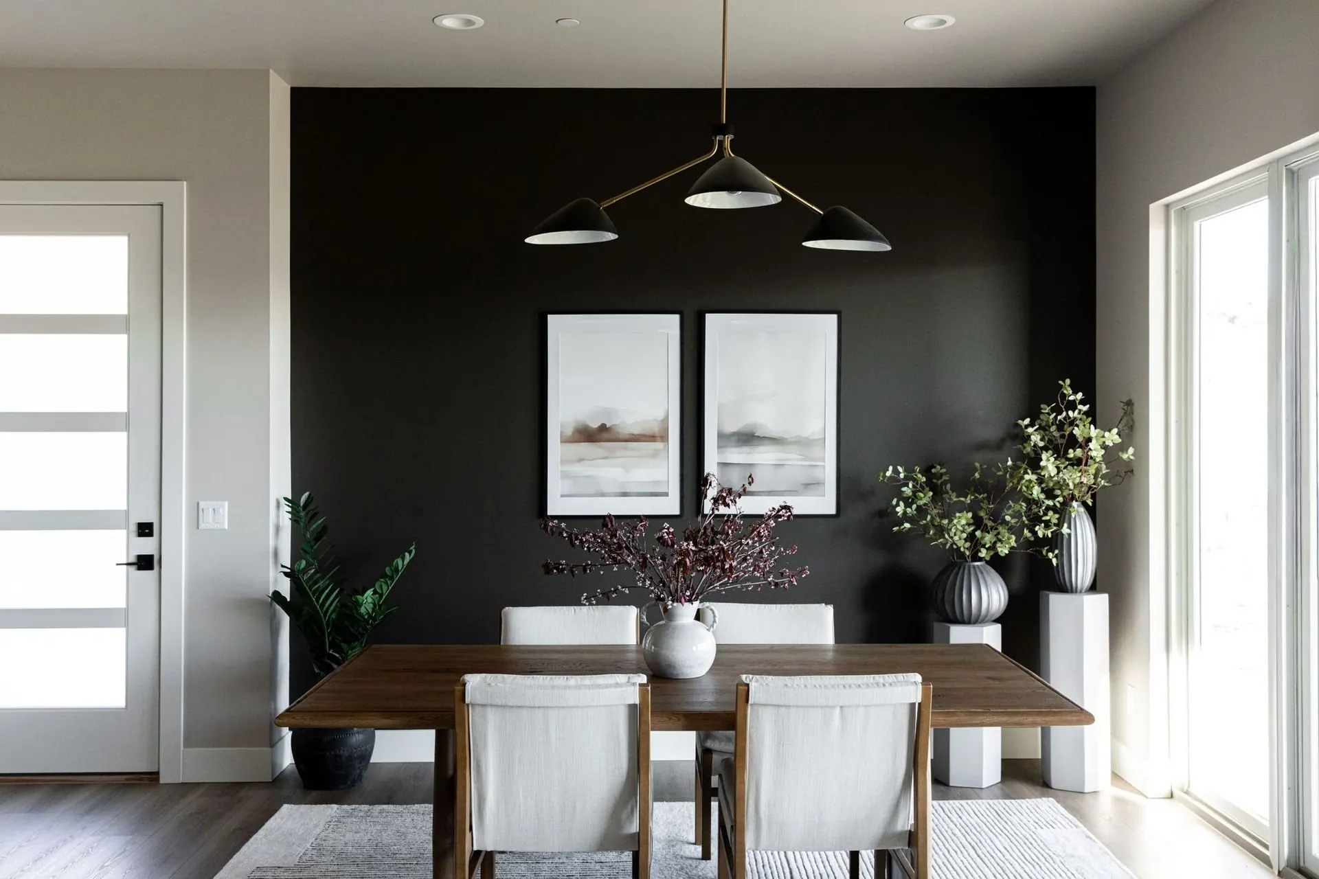 Dining room with a deep charcoal accent wall, black linear pendant, and light wood table