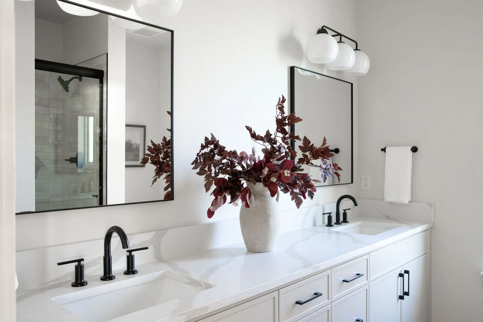 Double vanity with white cabinetry, matte black fixtures, and framed mirrors in a custom home