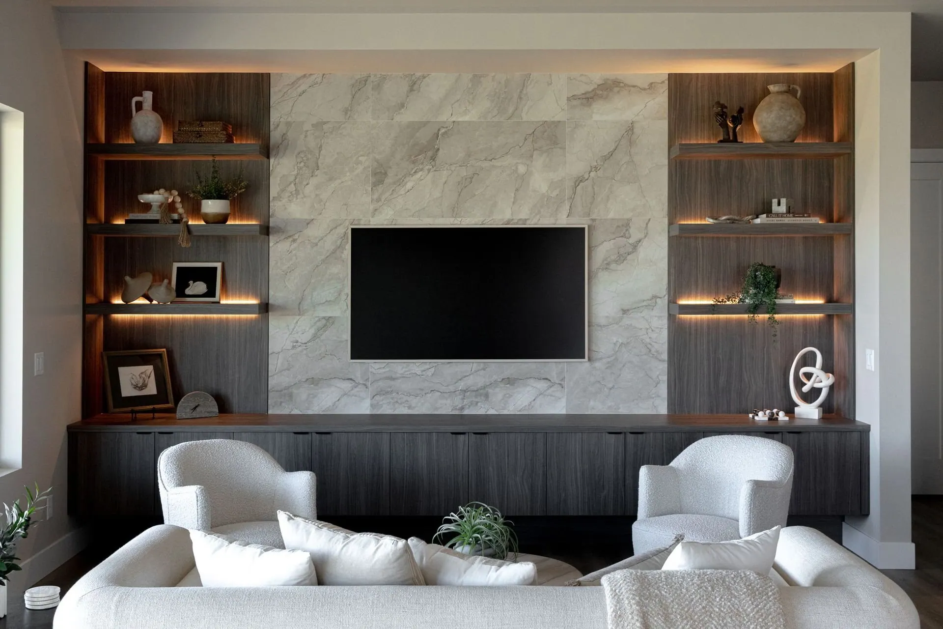 Living room with a marble fireplace surround, integrated media wall, and warm wood built-in shelving