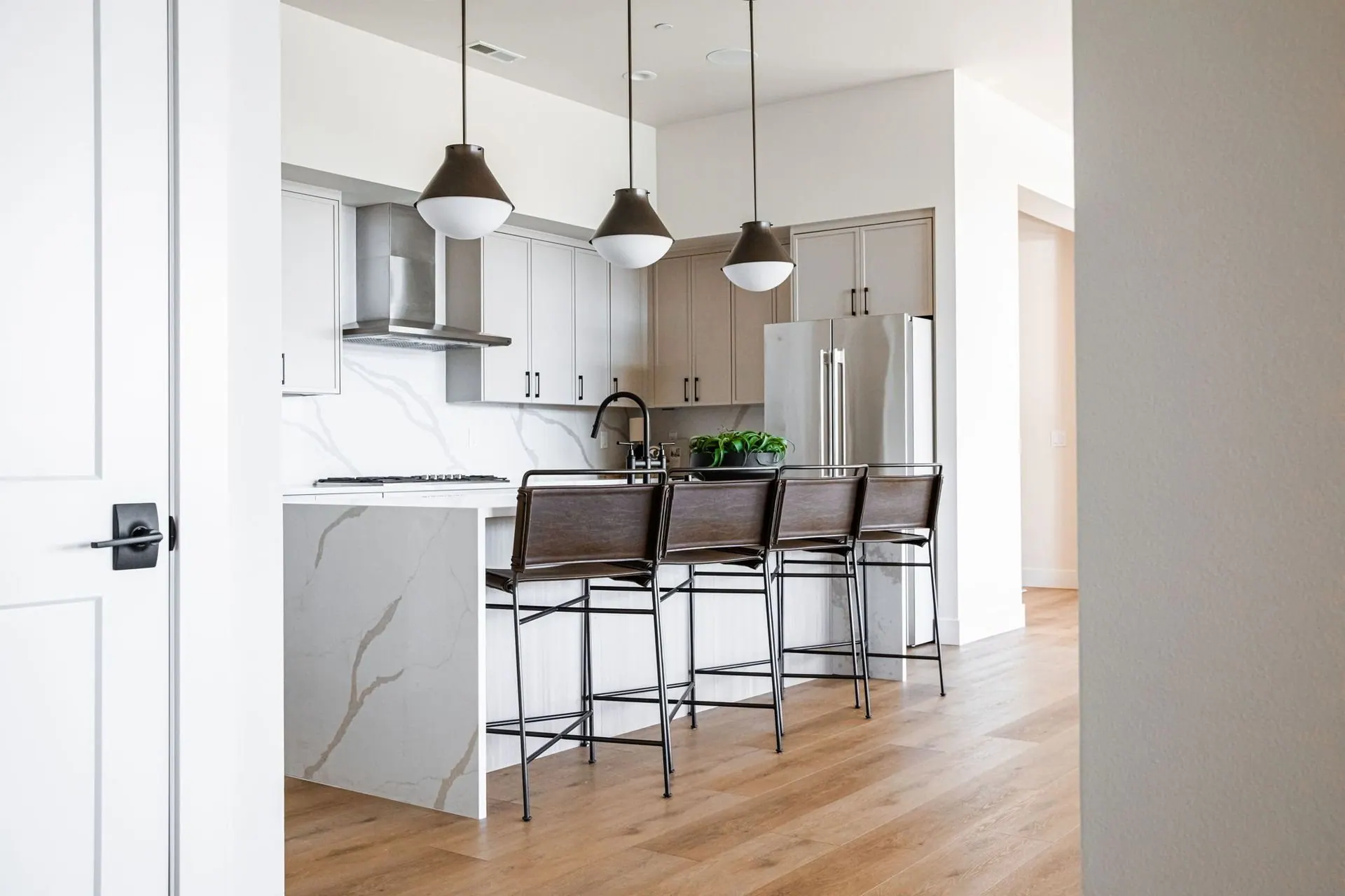 Open kitchen with dark pendant lights, a long island, and wide plank wood flooring