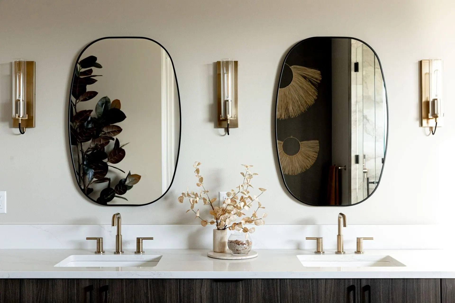Remodeled bathroom with a double vanity, oval mirrors, and stone countertops