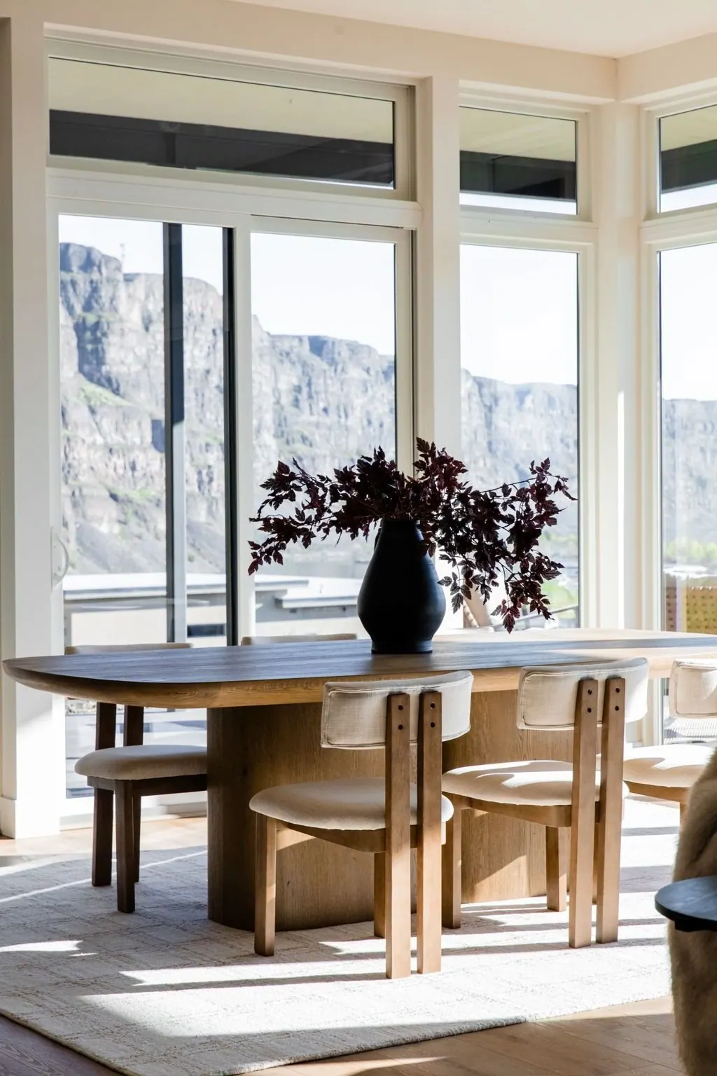 Round dining table set beside a tall window that frames the valley beyond